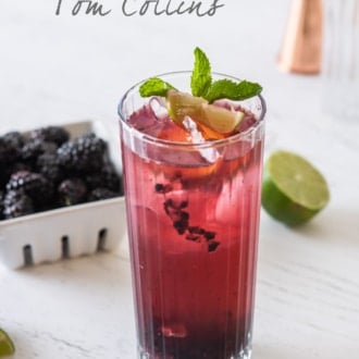 Blackberry Tom Collins with basket of blackberries behind cocktail