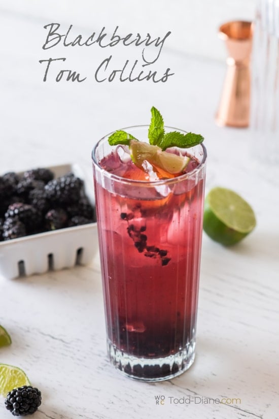 Blackberry Tom Collins with basket of blackberries behind cocktail