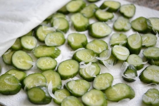 Cucumber and onion slices on a paper towel lined sheet pan