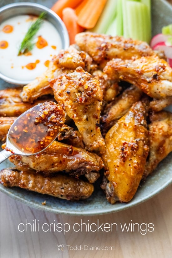 spooning chili oil over chili crisp chicken wings 