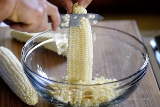 Cutting corn kernels off of cob over a bowl