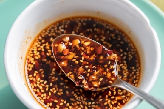 Dumpling sauce in a spoon over bowl