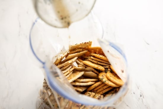 Pouring seasoning over crackers