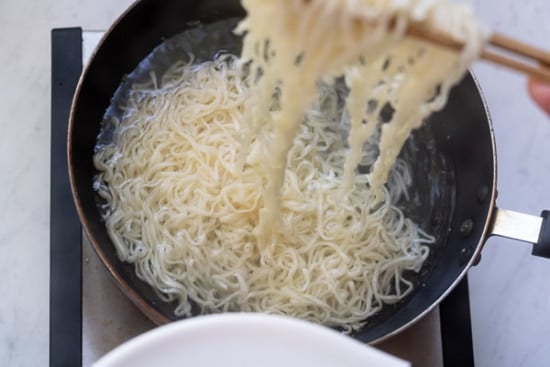 Lifting noodles out of pot of boiling water