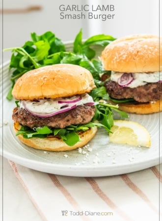 loaded garlic lamb smash burgers on plate with arugula