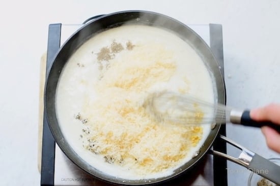 Whisking in parmesan cheese and herbs to the sauce