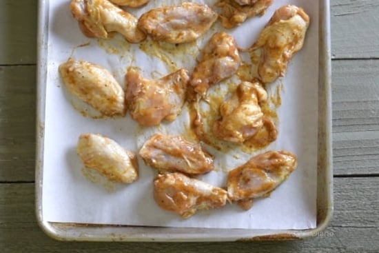 Uncooked sauced wings on baking sheet pan