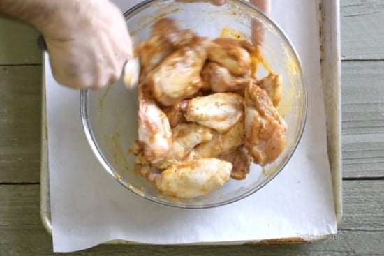 Tossing the raw chicken wings with sauce
