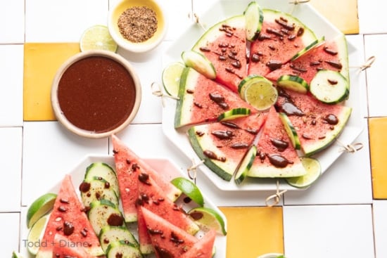 Finished platter with watermelon, cucumber, lime wedges, tajin and chamoy drizzles