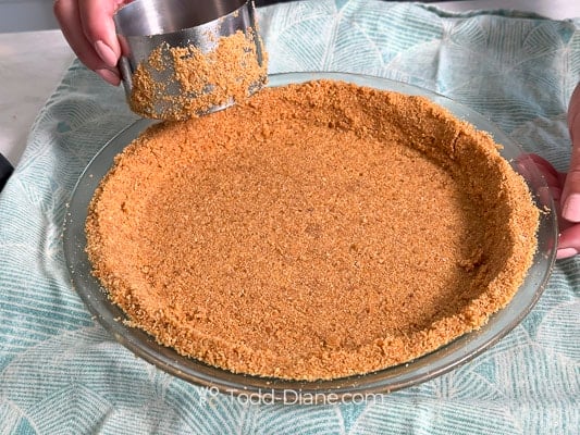 packing the graham crust into pie plate