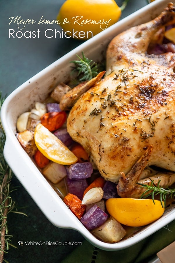 Lemon herb roast chicken recipe with fresh herbs and lemon in a baking dish close up