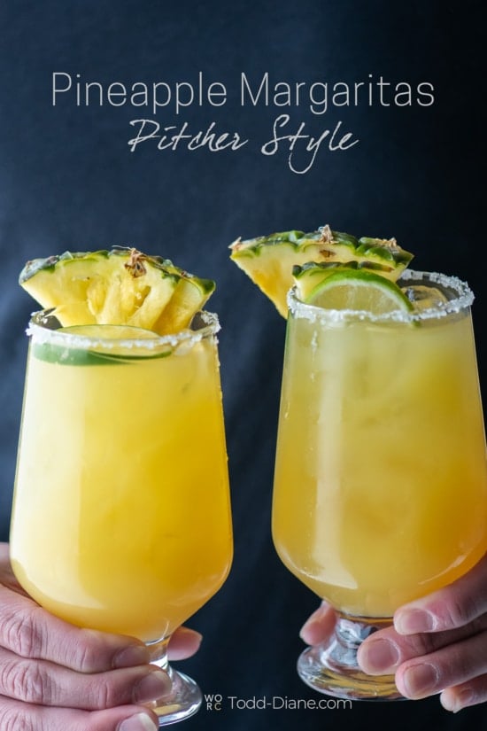 holding glasses of pitcher pineapple margarita 