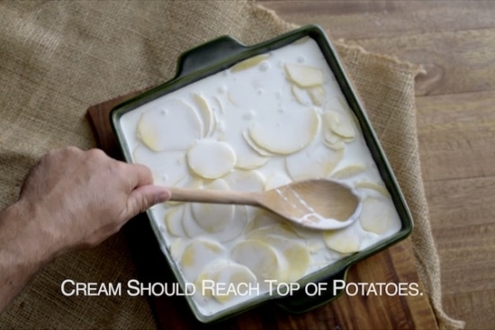 Pressing down on potatoes with spoon to see cream amount