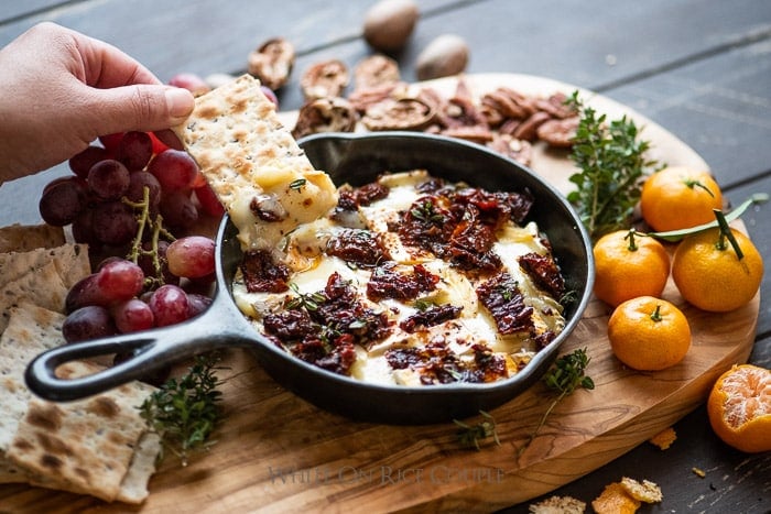 Baked Brie Dip Recipe with Garlic Sun Dried Tomato cracker dipping into dip