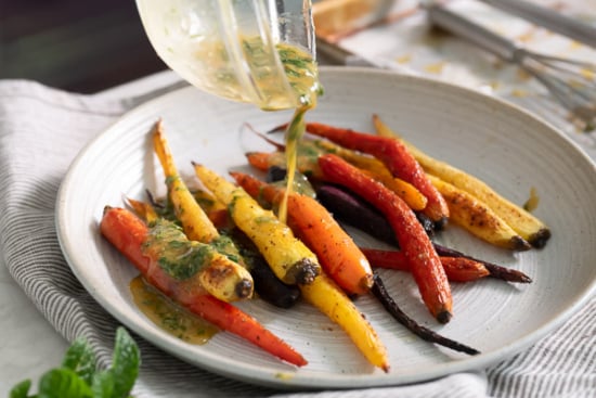 Pouring sauce over roasted carrots