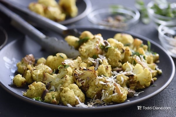 Grabbing finished curried cauliflower with tongs