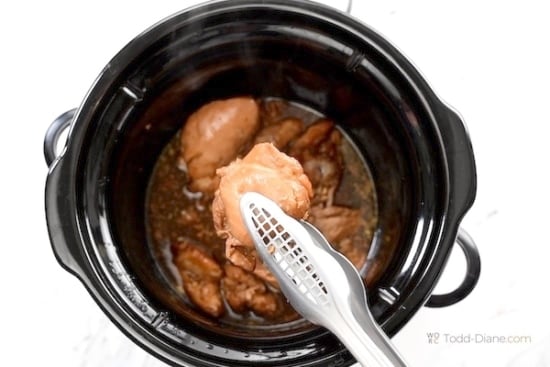 Holding cooked chicken above the slow cooker