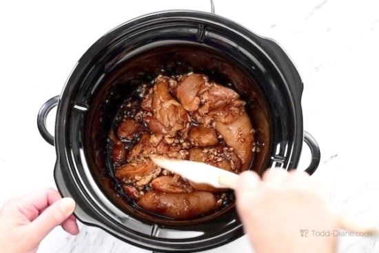 Pushing down the uncooked ingredients in the slow cooker