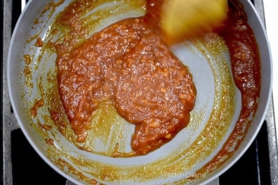 Stirring the simmering sriracha sauce in skillet