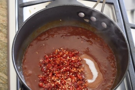 Tomato sauce, sugar, and chilies added to pan