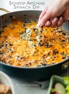 chip dipping into hot stovetop artichoke spinach dip