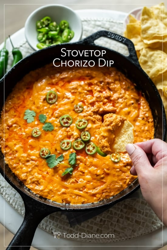 hand with chip dipping into stovetop chorizo cheese dip
