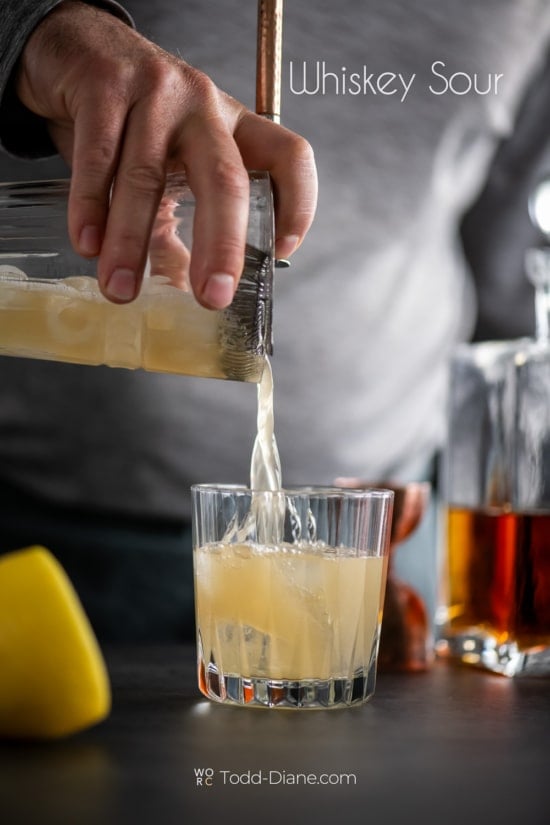 pouring whiskey sour cocktail 