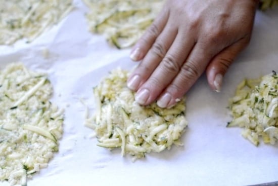 Patting zucchini tortillas into shape on a parchment lined baking pan