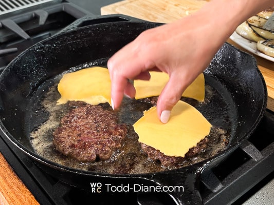 adding cheese to burger patty
