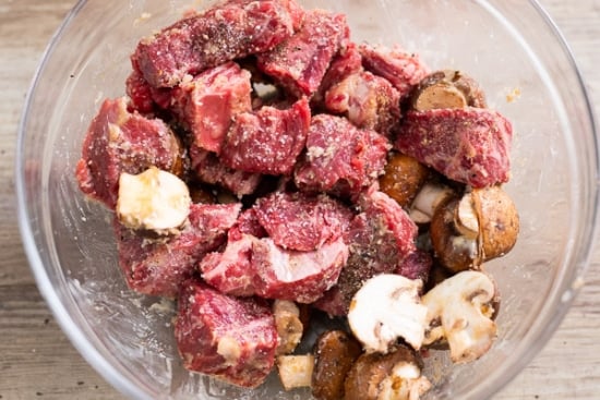 Raw steak bites seasoned in a mixing bowl