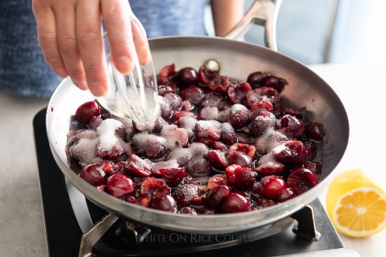 Pouring sugar into saucepan with the split cherries