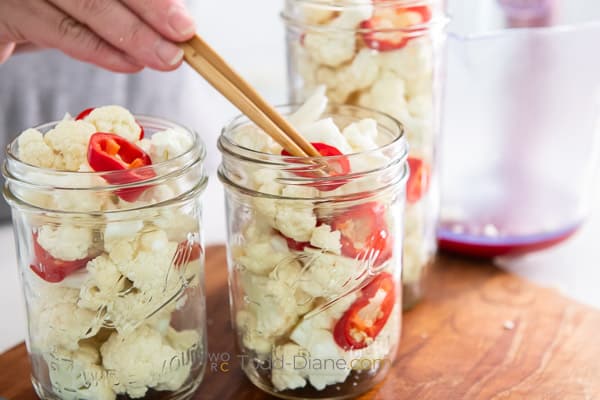 layering cauliflower and chiles in the jar