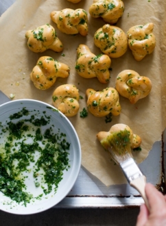 Brushing garlic knots with herbed butter