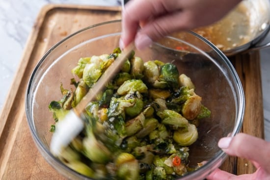 Tossing cooked brussels sprouts with sauce