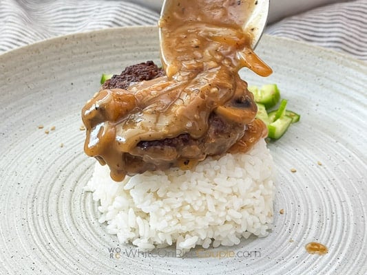 serving hamburger patty and gravy over rice