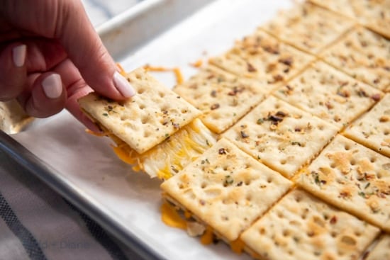 Pulling a cracker filled with cheese from the rest of the tray