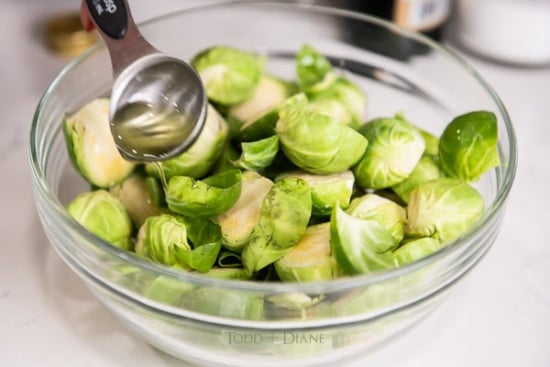 Pouring tablespoon of oil over brussels sprouts