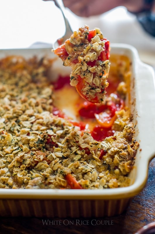 Savory tomato crisp on a spoon in a baking dish
