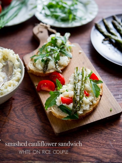 Smashed cauliflower sandwich recipe with roasted asparagus on toast on a cutting board