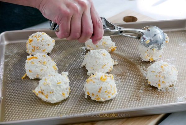scooping out biscuit dough on sheet pan
