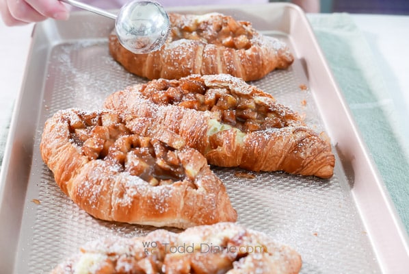 dusting powdered sugar over cooked croissants