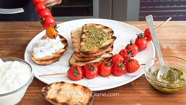Serving grilled tomato skewers with bread, pesto, and ricotta